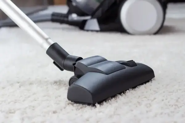 Elektrikli süpürge başlığı halıyı temizliyor.