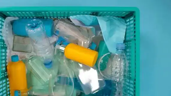 Mavi bir sepet içinde karışık plastik atıklar ve bir yüz maskesi.