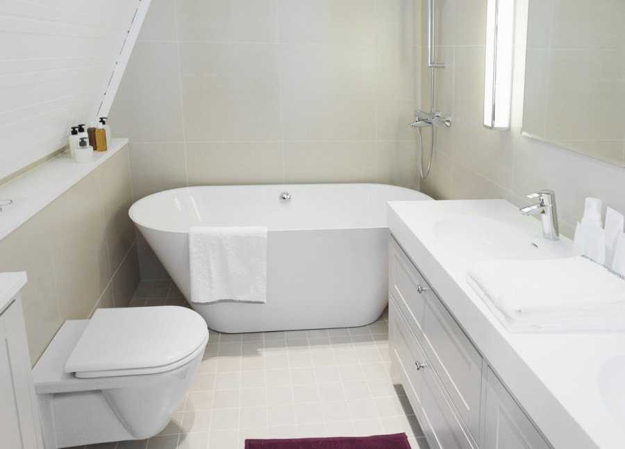 Beyaz temiz bir banyo, oval küvet, lavabo ve tuvalet görülmekte.