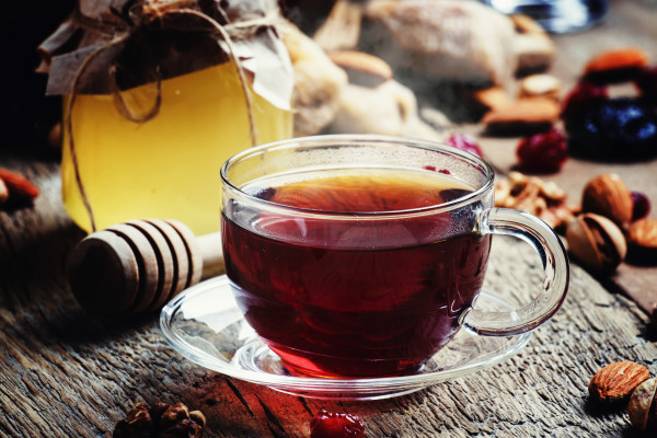 Bir fincan çay, bal kavanozu ve kuru yemişler.