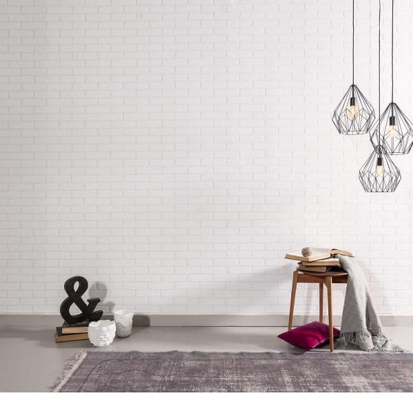 Beyaz tuğla duvara asılı modern avizeler, yanında ahşap sandalye ve üzerinde kitaplar ve battaniye bulunan minimalist bir oda.