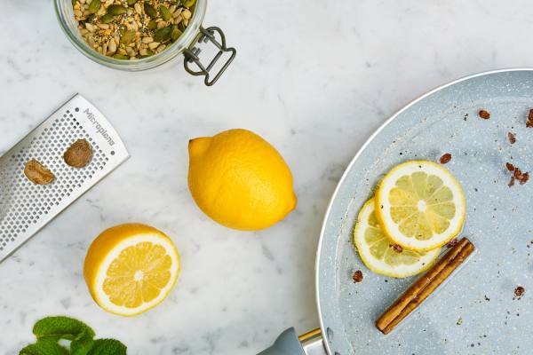 Masa üzerinde limon dilimleri, tam limon, rende, karışık baharatlar ve tarçın çubuğu.