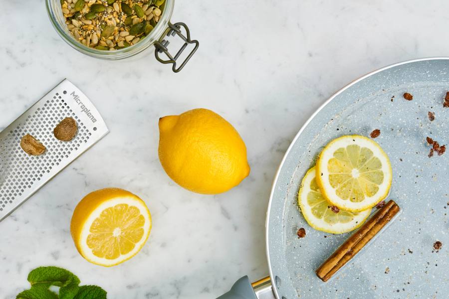 Masa üzerinde limon dilimleri, tam limon, rende, karışık baharatlar ve tarçın çubuğu.