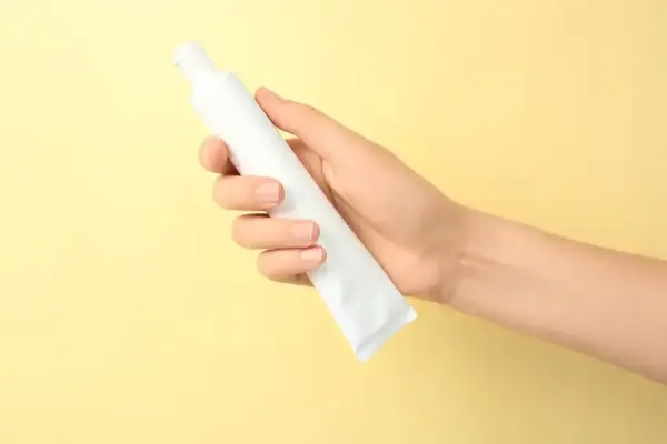Sarı arka planda temizlik spreyi tutan el.