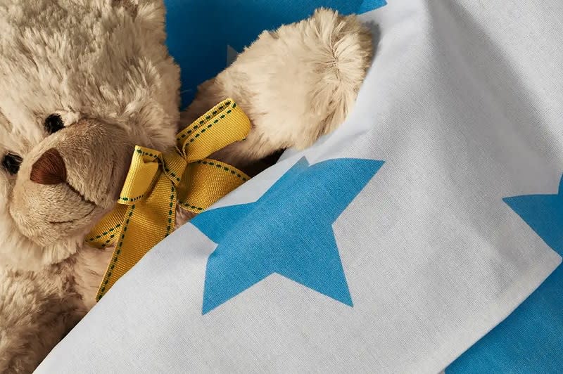 Sarı kurdele bağlı peluş ayı ve mavi yıldız desenli kumaş.