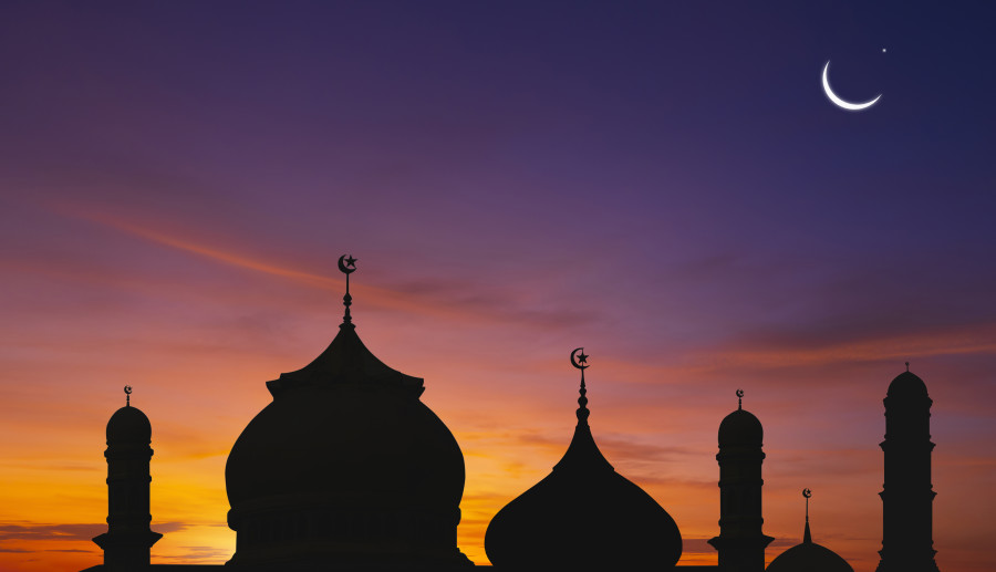 Hilal ay ve yıldız, cami kubbeleri ve minarelerinin siluetleri ile gün batımı.