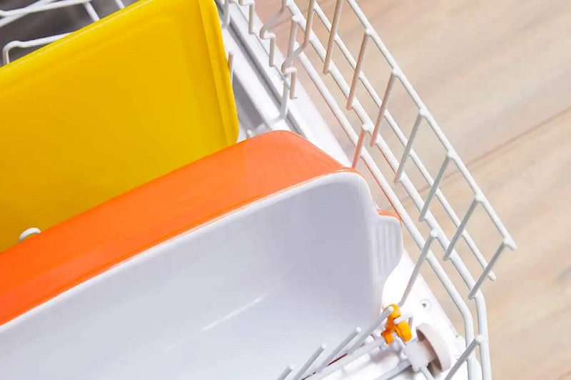Bulaşık makinesinde sarı ve turuncu plastik kaplar.