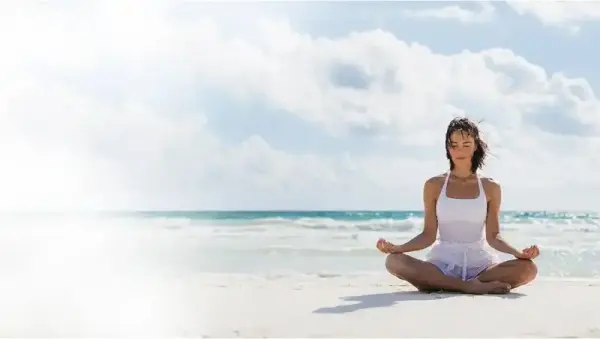 Plajda meditasyon yapan bir kadın.