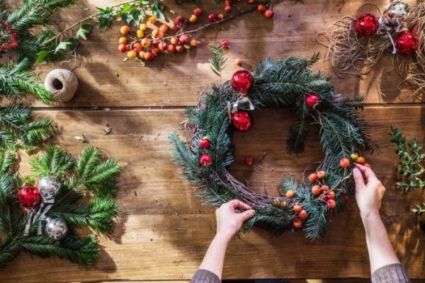 Çam dalları ve Noel süsleriyle süslenmiş bir çelenk yapımı.