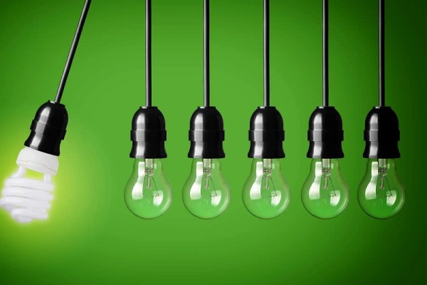 Yeşil bir arka plan üzerine sıralı halde asılı bir düşük enerjili ampul ve dört adet klasik ampul.