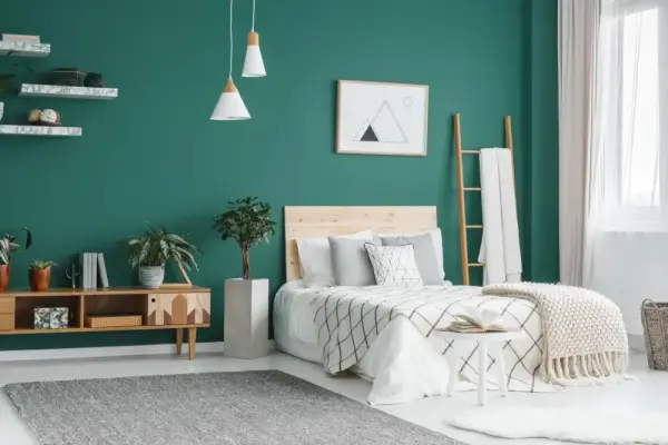 Yeşil duvarlı ve modern mobilyalarla döşenmiş düzenli bir yatak odası.