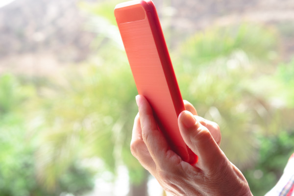 Kırmızı akıllı telefon tutan bir kişinin eli.