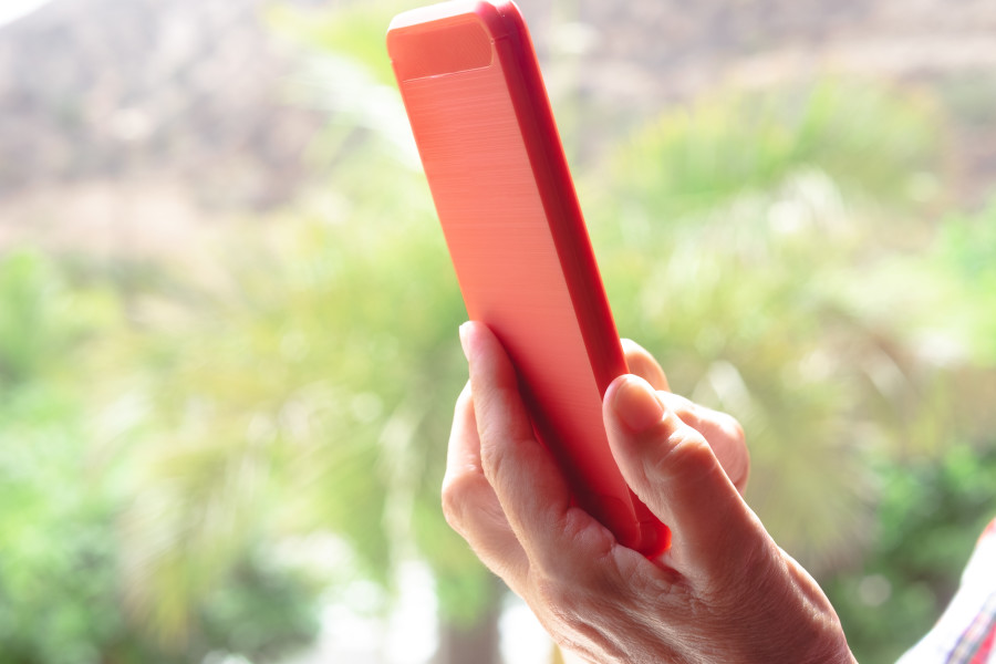 Kırmızı akıllı telefon tutan bir kişinin eli.