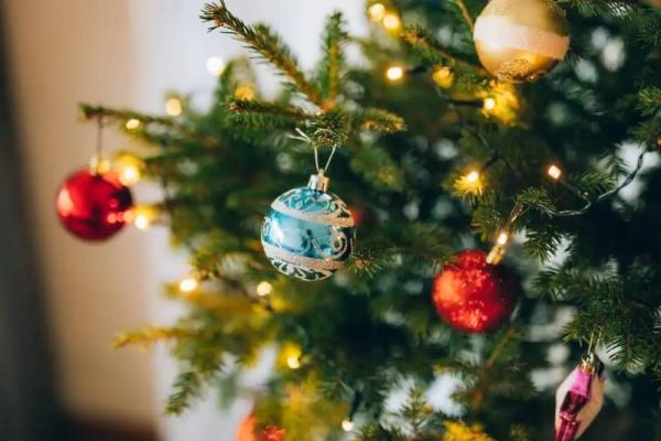 Işıklarla süslenmiş ve renkli süsler asılmış bir Noel ağacı parçası.