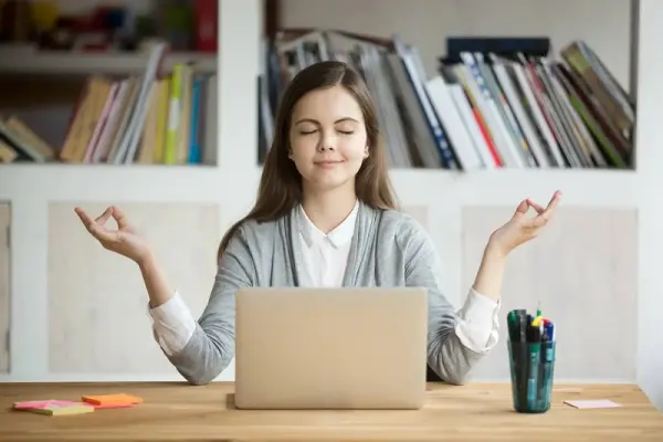 Dizüstü bilgisayar önünde meditasyon yapan kız.