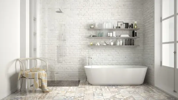 Banyo içinde beyaz seramik duvarlar, serbest duran bir küvet ve duvar rafı görünmektedir.