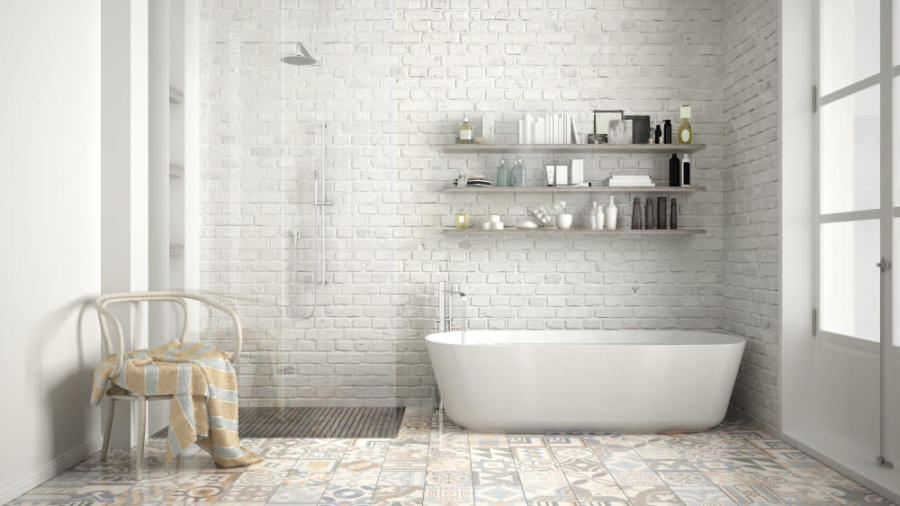 Banyo içinde beyaz seramik duvarlar, serbest duran bir küvet ve duvar rafı görünmektedir.