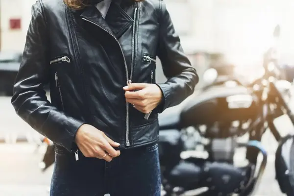 Deri ceket giyen bir kişi ve arka planda bir motosiklet.