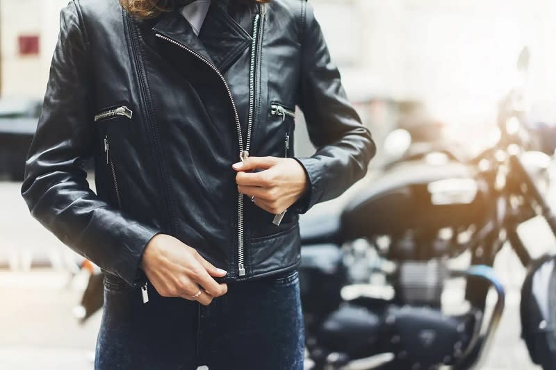 Deri ceket giyen bir kişi ve arka planda bir motosiklet.