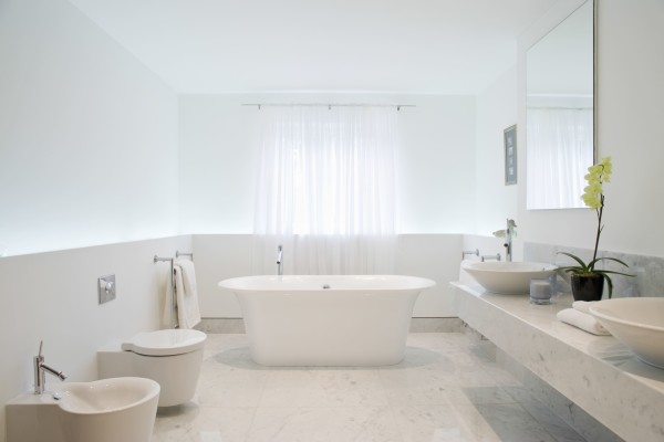 Beyaz ve modern bir banyo, mermer zemin, bağımsız küvet, lavabo ve tuvalet.