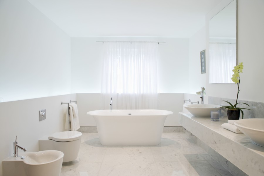 Beyaz ve modern bir banyo, mermer zemin, bağımsız küvet, lavabo ve tuvalet.