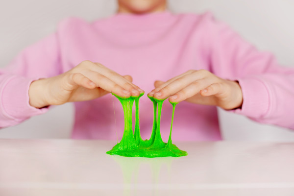 Pembe kazaklı bir kişi yeşil bir slime ile oynuyor.