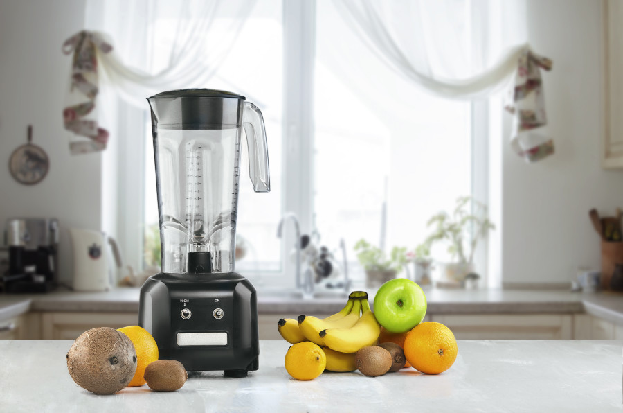 Mutfak tezgahı üzerinde blender ve yanında çeşitli meyveler.