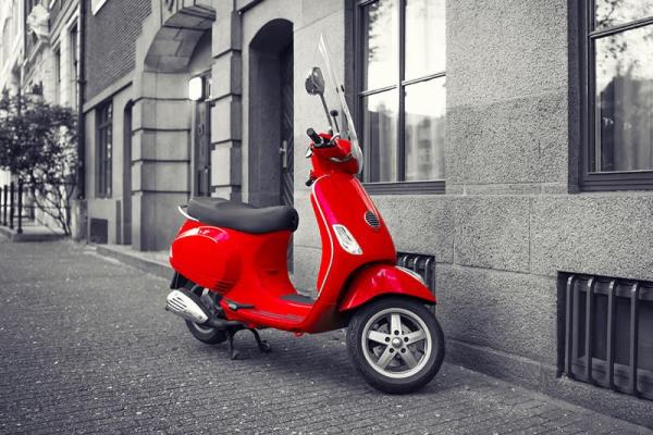 Bir binanın yanına park edilmiş kırmızı bir scooter.